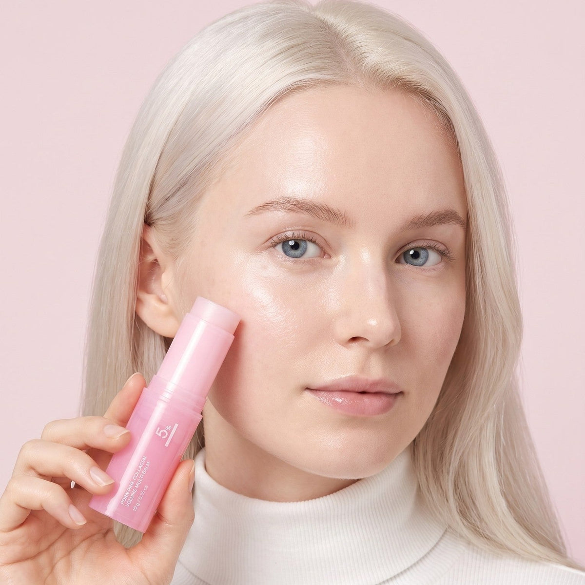 Femme blonde tenant un Stick Repulpant contre sa joue Bio-Collagène & PDRN
